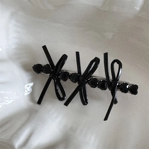 Detail of black faux leather bow hair clip with heart-shaped crystal on silver base