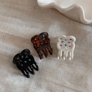 Detailed view of floral hair claws in black, tortoiseshell, and cream with rhinestones