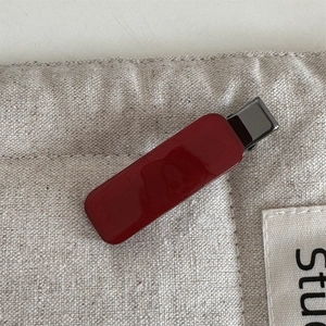 Close-up of a glossy red rectangular acetate hair clip on rustic linen fabric