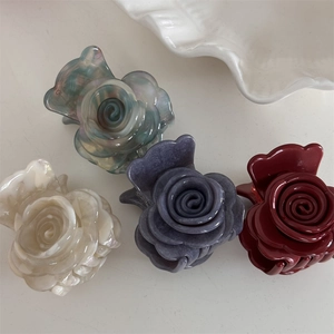 Vista plana de cuatro pinzas para el cabello con flores en verde, morado, crema y burdeos
