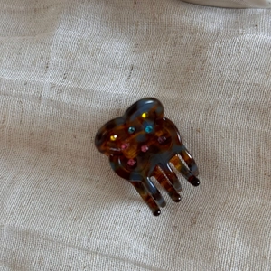 Close-up of tortoise shell pattern hair claw clip with colorful rhinestones on burlap