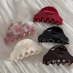 Five assorted colors of acetate hair claws on a cream fabric background set
