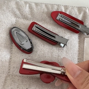 Detail of red acetate hair clips showing the durable silver metal alligator clip mechanism