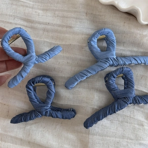 Detail view of denim fabric wrapped hair claw clips with spiral twist rope design and metal spring