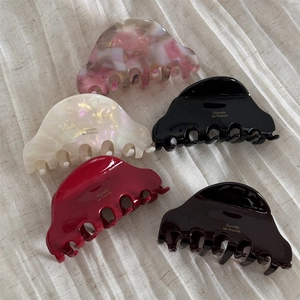 Flat lay of acetate hair claws in marble pink, pearl white, and deep brown finishes