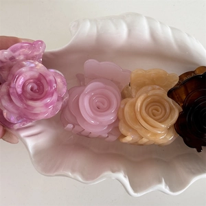Primer plano de cuatro pinzas para el cabello con forma de rosa en violeta, rosa y beige