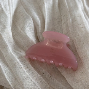 Close-up of translucent pink jelly hair claw clip on white linen fabric background