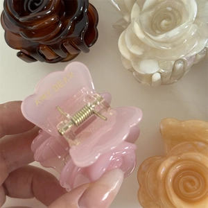 Detalle de pinzas de pelo con forma de rosa de acetato con capas de pétalos y logotipo