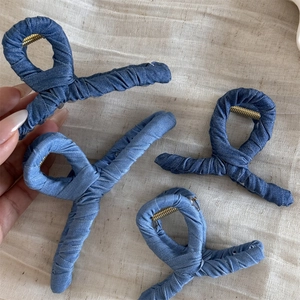 Denim wrapped hair claw clips in blue shades shown on a textured beige background