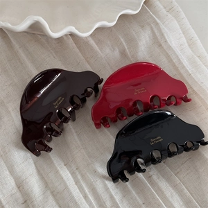 Three medium acetate hair claws in brown, red, and black with elegant gold logo lettering