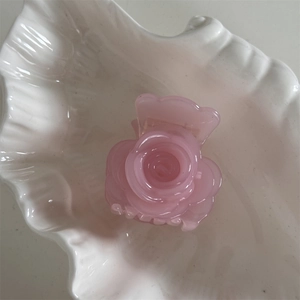 Primer plano de una pinza para el cabello de rosa en acetato sobre un plato blanco