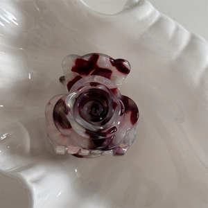 Detalle de una pinza para el pelo con forma de flor, acetato veteado púrpura y brillos