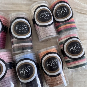 Detail view of multi-color velvet hair ties set in transparent cylindrical packaging tubs