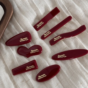 8-piece set of wine red geometric hair clips with gold lettering on linen fabric