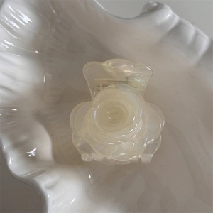 Detalle de la pinza para el cabello con forma de rosa crema en una bandeja de cerámica