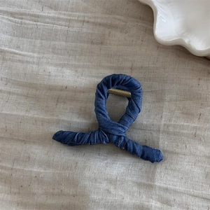 Close-up detail of denim fabric texture on stylish shark hair claw clip with metal spring