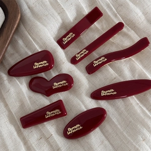 7-piece set of wine red hair clips with gold French lettering on elegant beige fabric