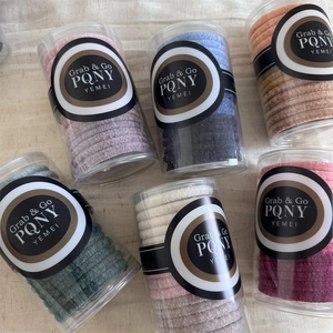 Macro shot of colorful velvet hair ties in various shades inside clear cylinder containers