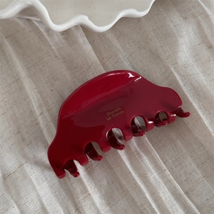 Close-up of a burgundy acetate hair claw clip with golden Barrette La France text