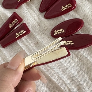 Close-up of wine red resin hair clips with golden metal base and Barrette lettering