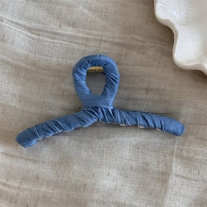 Close-up of denim fabric wrapped hair claw clip with golden metal spring detail
