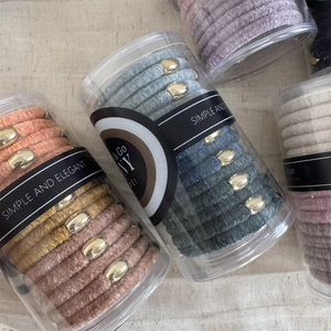 Close-up of velvet hair ties in Morandi colors with gold buckles in clear tubes