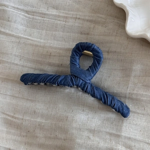 Detail shot of navy blue denim wrapped hair claw clip with golden metal spring