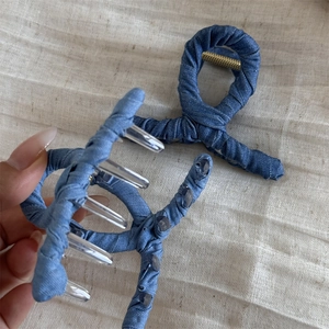 Detail of denim fabric wrapped hair claw clips in blue shades with transparent resin teeth