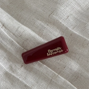 Close-up of wine red rectangular hair clip with gold Barrette La France lettering