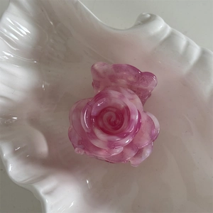 Detalle de pinza de pelo rosa con brillo y textura floral en bandeja de concha