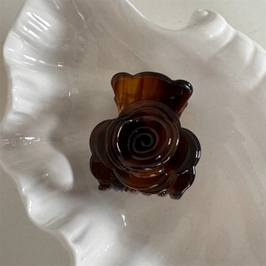 Detalle de una pinza para el cabello de rosa ámbar sobre una bandeja de cerámica blanca