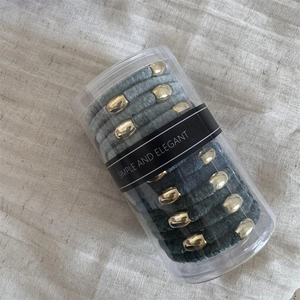 Detail of velvet hair ties with gold beads in a simple and elegant cylinder storage case
