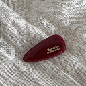 Macro shot of a glossy dark red hair clip with golden Barrette LaFrance text on fabric