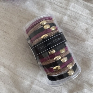 Three-color velvet hair ties with golden oval metal charms in a clear cylinder package