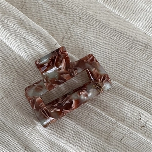 Close-up of tortoise shell pattern acetate hair claw clip on soft fabric background