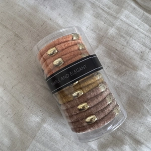 Detailed view of elastic velvet hair ties with gold buckles in a clear cylinder container