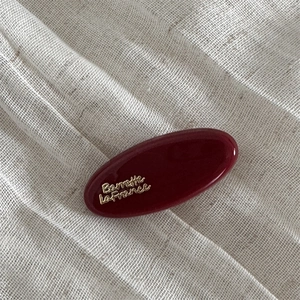 Close-up of a dark red oval hair clip with gold Barrette La France text detail