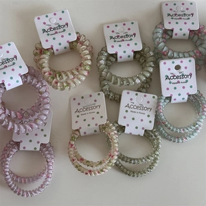 Set of two colorful polka dot spiral hair ties in pink and green on display cards