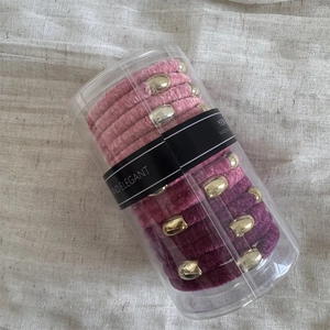 Detailed view of elastic velvet hair ties set with gold beads in transparent cylinder