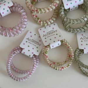 Close-up of floral spiral hair ties in pink and green with Korean accessory packaging