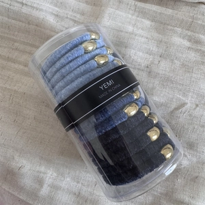 Detail of blue velvet hair scrunchies with gold metal beads in a transparent case