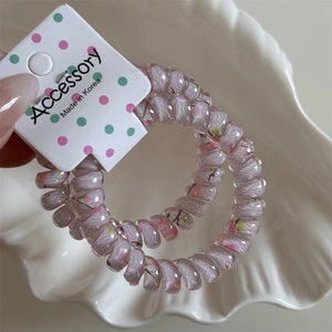 Close-up of pink floral spiral telephone wire hair ties on a white accessory card
