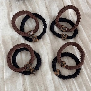 Elastici per capelli leopardati con ciondoli a cuore e stella su sfondo beige