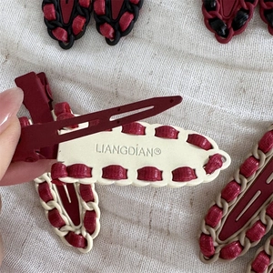 Detailed view of woven red leather and alloy hair clip with premium vintage texture