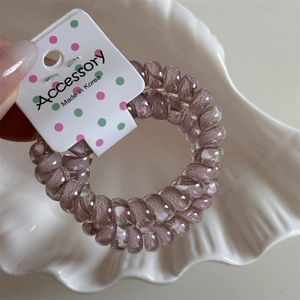 Pink spiral hair tie with colorful speckles on white polka dot display card