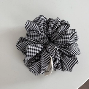 Detail eines schwarz-weißen Gingham-Haargummis mit gewebtem Markenetikett am Rand