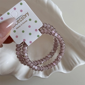 Close-up of pink and purple spiral hair ties on polka dot card in a ceramic shell tray