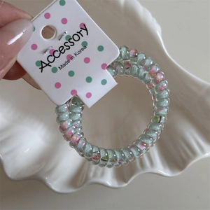 Detail of floral pattern telephone wire hair coil held on a white Accessory card tag