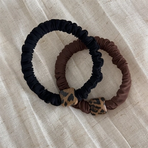 Dettaglio di elastici per capelli con perle leopardate quadrate su sfondo di lino