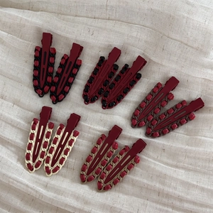Close-up of red leather and alloy hair clips with woven fabric details in various colors